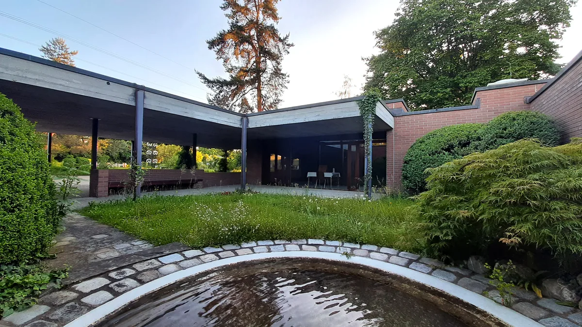 Düsteres Friedhofgebäude mit Sichtbeton und Backsteinmauern.